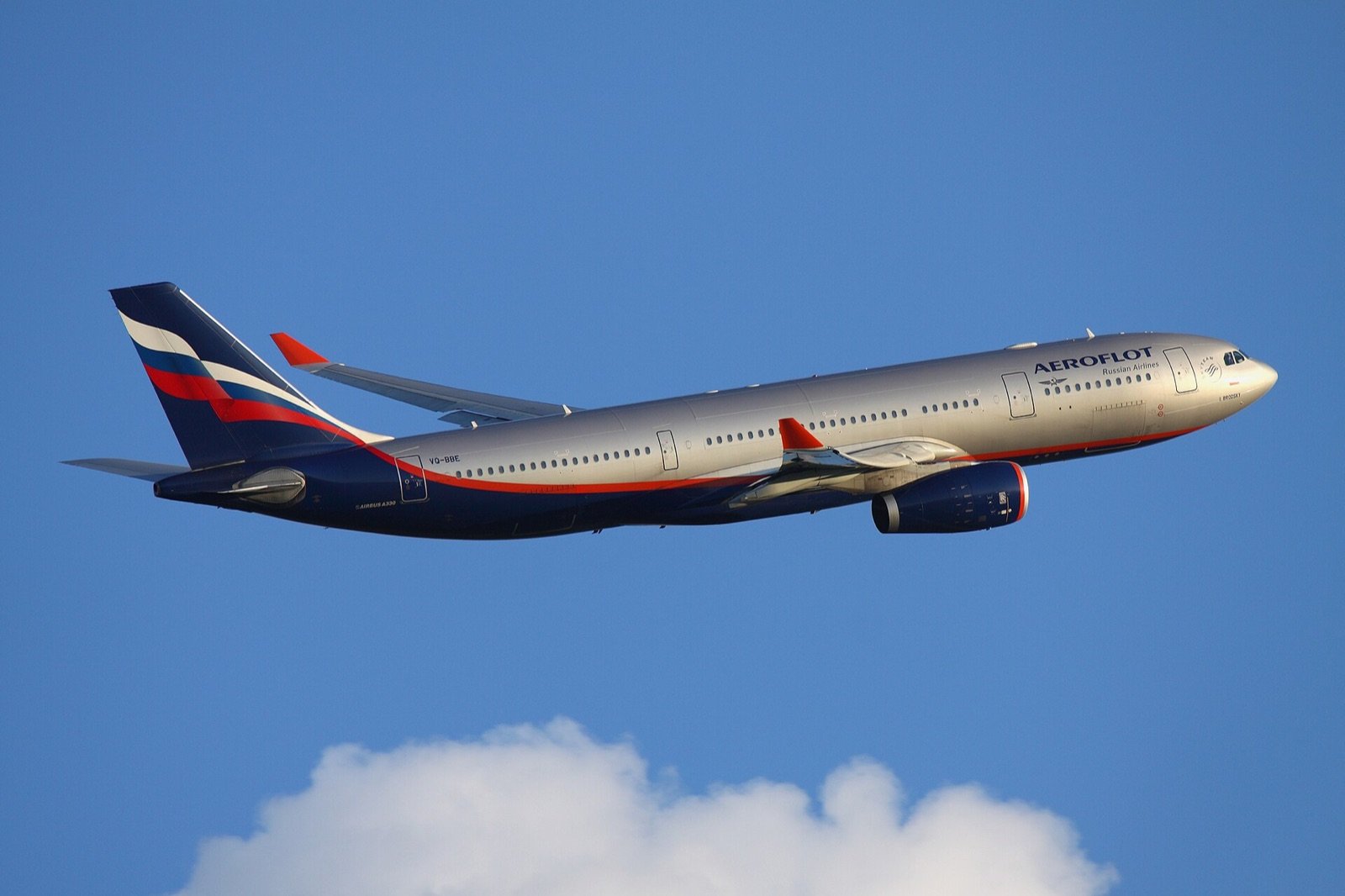 Wide-body passenger airplane flying above clouds in clear daylight