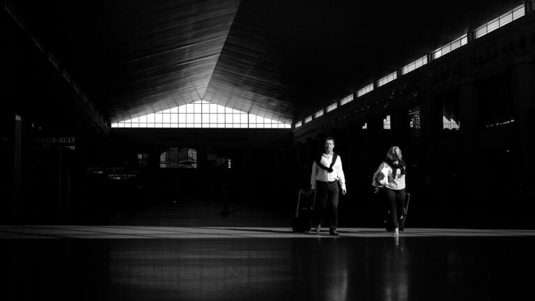 Travelers walking through an airport concourse with carry-on backpacks and luggage