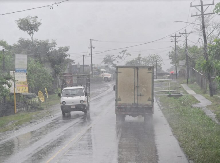 Cars and trucks traveling a wet two-lane road during heavy rain in Costa Rica