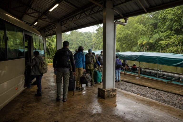 Travelers with soft luggage leaving a small bus for covered passenger boats at a wet forest river dock