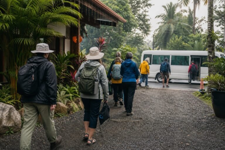Travelers in rain and sun gear boarding a small shuttle outside a Uvita guesthouse before a marine tour