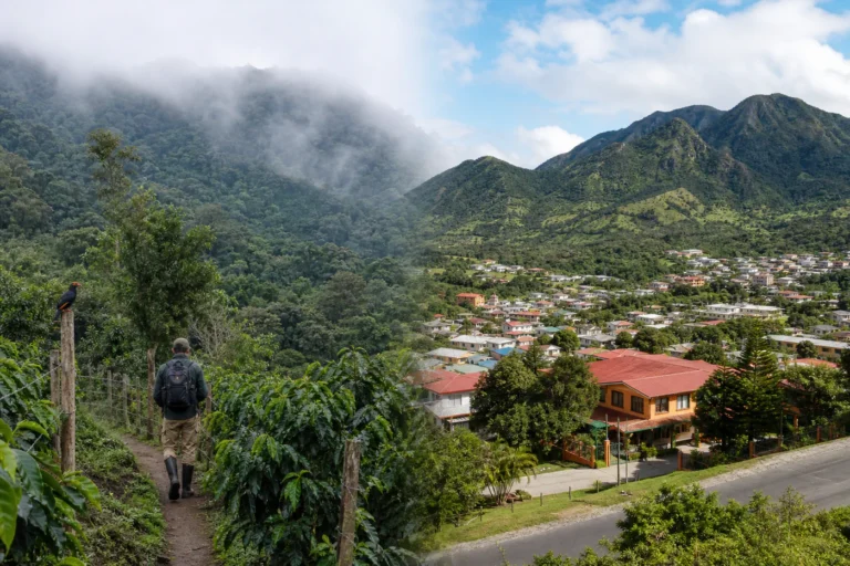 Split-scene editorial image showing misty Boquete coffee hills on one side and the greener crater town of El Valle de Anton on the other